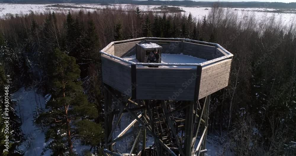 Cinema 4k aerial view away from a uncle and a boy on a observation tower, revealing the view of a huge swamp, on a cold winter day, in Torronsuo national park, Kanta-hame, Finland Cinema 4k aerial view away from a uncle and a boy on a observation tower, revealing the view of a huge swamp, on a cold winter day, in Torronsuo national park, Kanta-hame, Finland