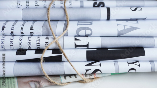 News - fresh newspapers with headlines and articles. Folded papers tied up with rope. Concept for business and communication