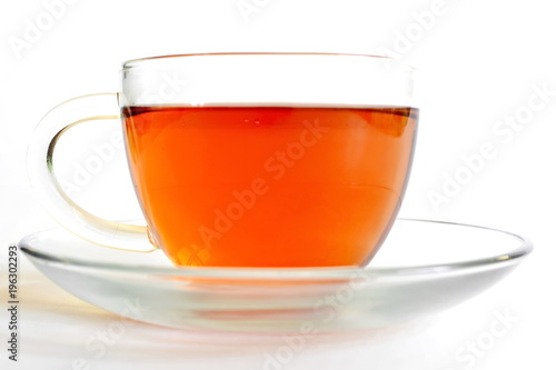 hot black tea in transparent glass cup on saucer on white background