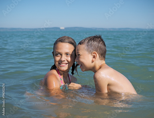 Little girl and littel boy playing in water