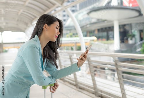 Free Download Beautiful cute girl smiling in business woman clothes holding a smart phone, urban city background - GFXLoad