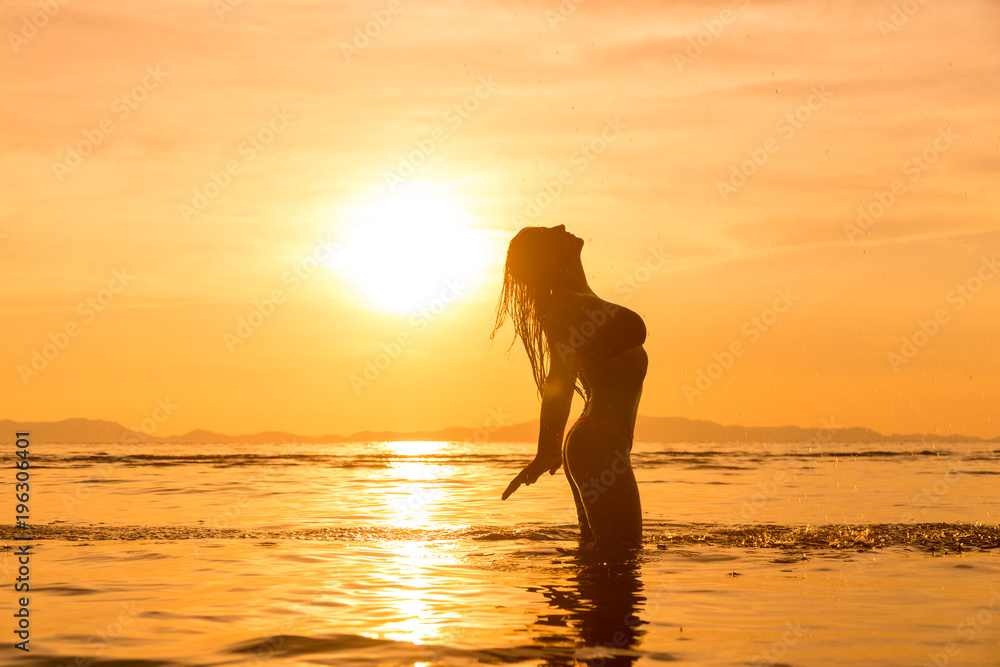 Silhouette of a young and fit woman on the beach at sunset