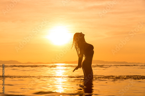 Silhouette of a young and fit woman on the beach at sunset