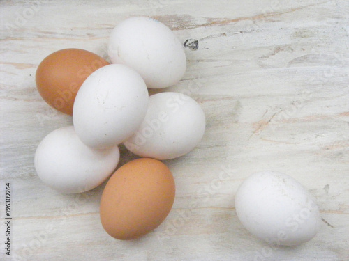 A lots of white and brown chicken eggs on white shabby background flat view
