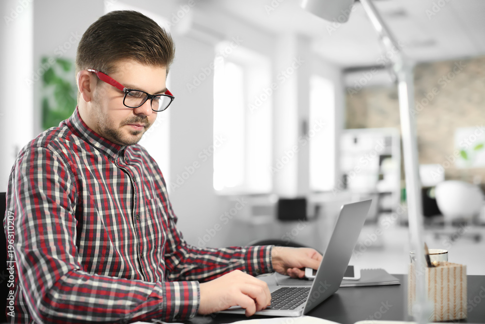 Young man with laptop working in office Young man with laptop working in office