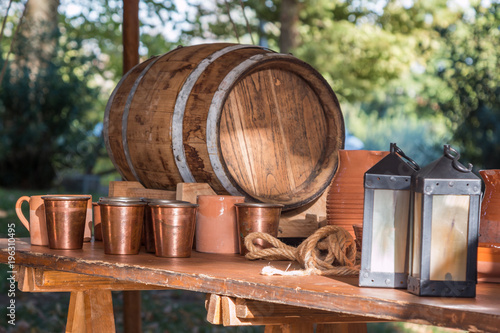 Antique Barrel, Brown Cups, Lamps and Copper Glasses on Wooden Table photo