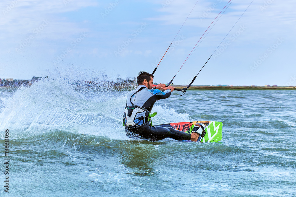 Naklejka premium Man riding a kite surfing on the waves in the summer.