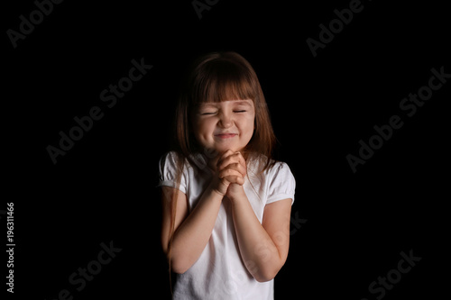 Obraz na plátně Religious Christian girl praying on black background