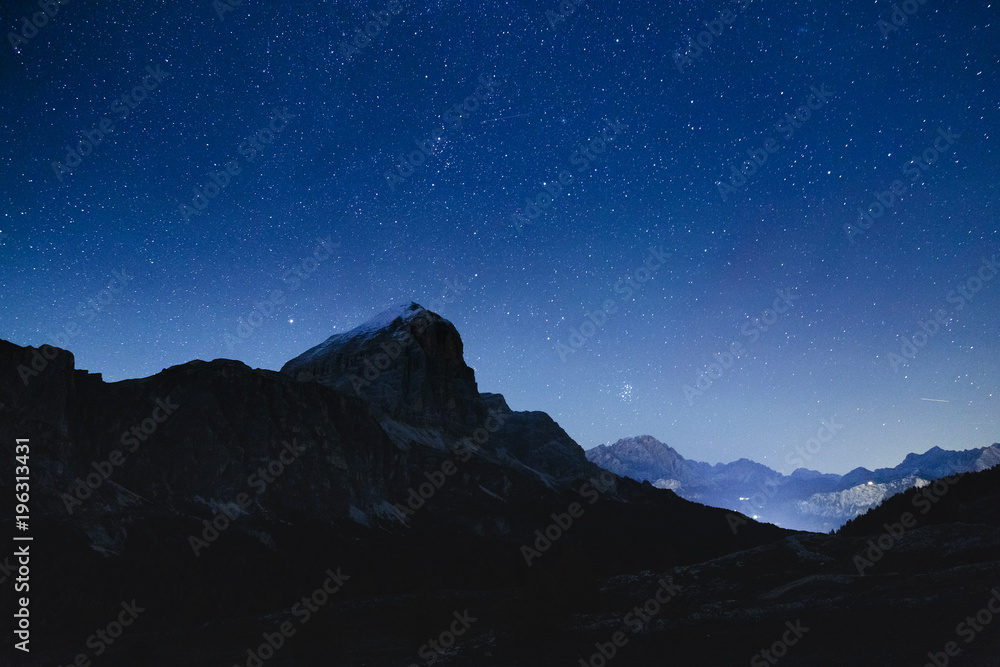 Night sky with stars in Dolomites Alps in Italy. View on Tofana di Rozes mountain ridge.