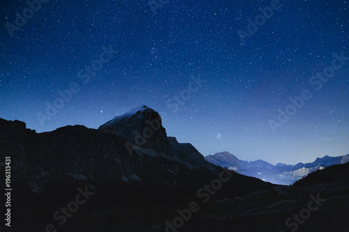 Night sky with stars in Dolomites Alps in Italy. View on Tofana di Rozes mountain ridge.