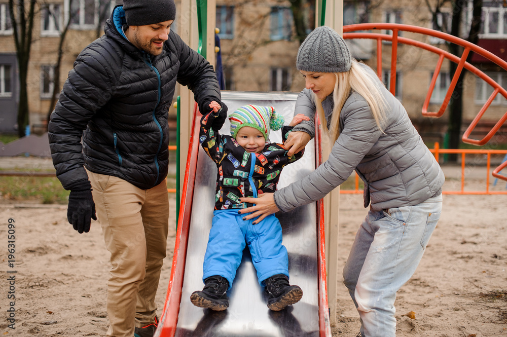 Cute toddler boy playing with father and mother on the playground Cute toddler boy playing with father and mother on the playground