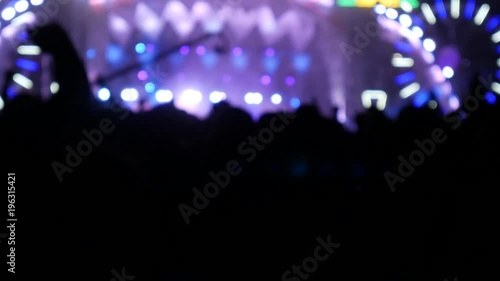 Blurred background of colored lights from the stage at a live music festival at night. Blur people dancing to the rhythm of the music. Light and color with beautiful in the concert at