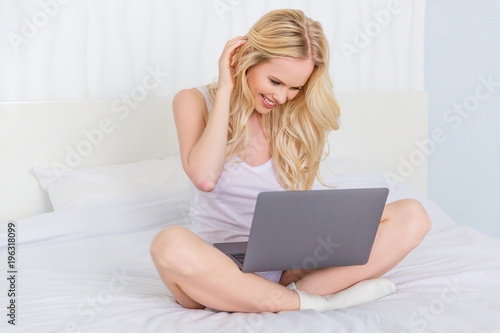 beautiful happy young woman using laptop on bed