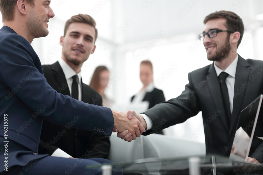 Partners concluding deal and shaking hands in the presence of team members Partners concluding deal and shaking hands in the presence of team members