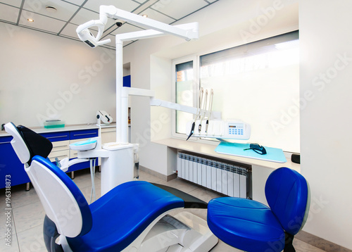 Interior of new modern dental clinic office room with chair in blue and white colors. Dentistry  stomatology  medicine medical equipment concept in teeth cabinet