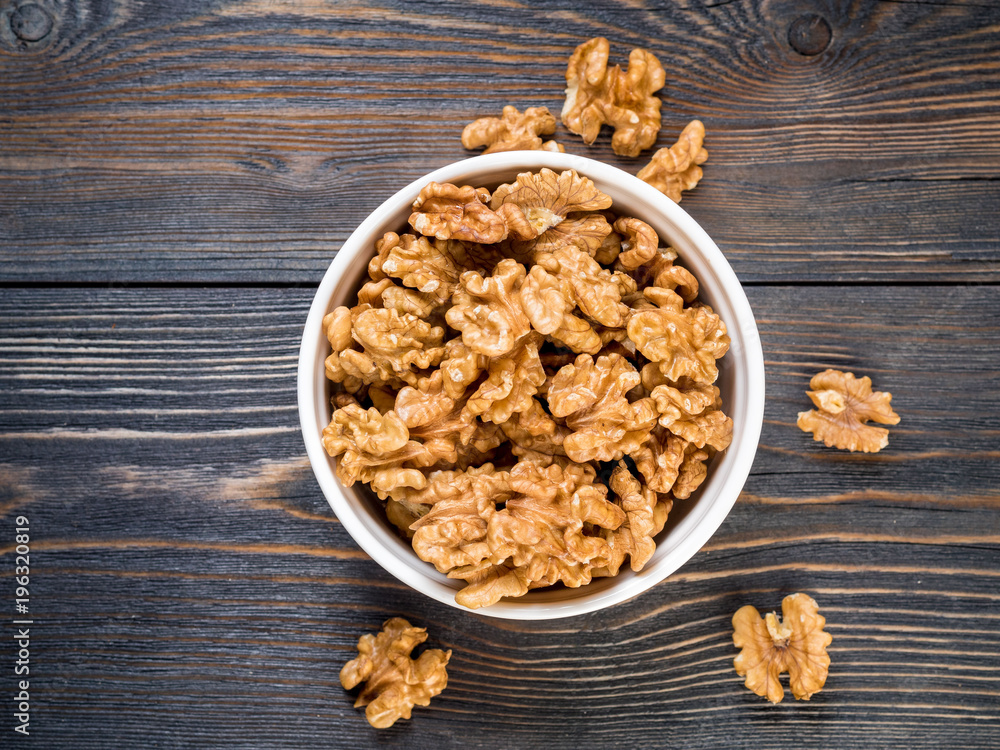 Top view of glass jar with a handful of walnut, circassian nuts on a wooden dark background. Top view of glass jar with a handful of walnut, circassian nuts on a wooden dark background.