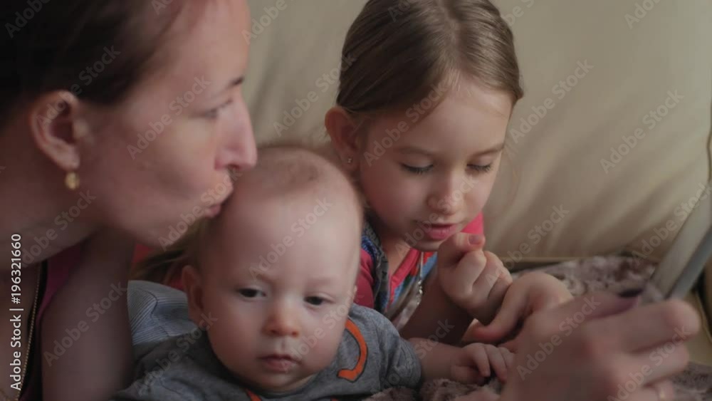 Mother and children with a tablet computer at home watching cartoons and playing. Mother and children with a tablet computer at home watching cartoons and playing.