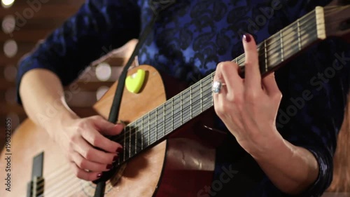 Hands on the strings of an acoustic guitar. Close-up. Focus sharpness moves from one hand to the other. A girl in a blue dress is playing a musical instrument. photo