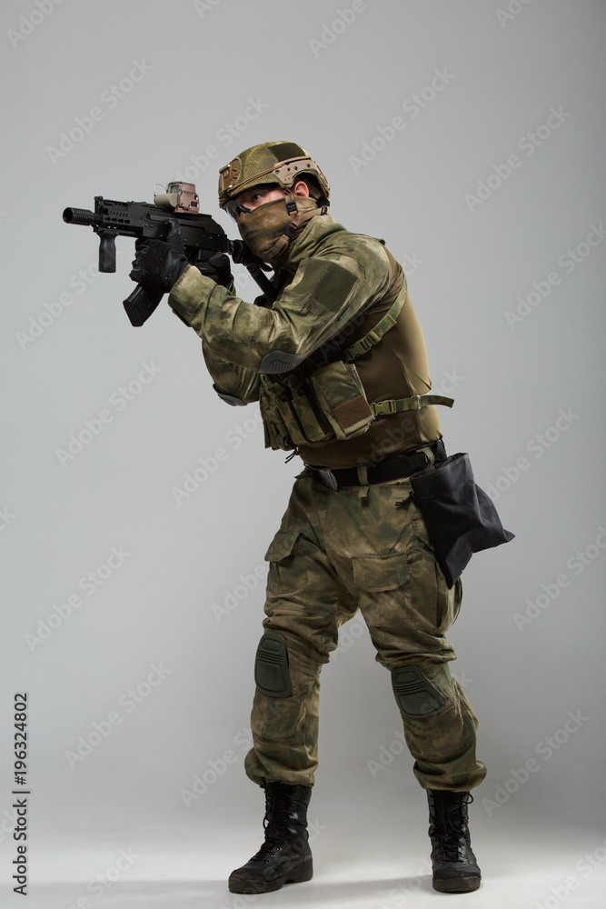Full-length photo of soldier in camouflage with gun Full-length photo of soldier in camouflage with gun