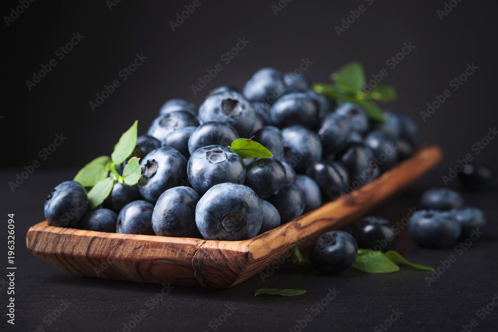 Blueberries in old wooden dish .