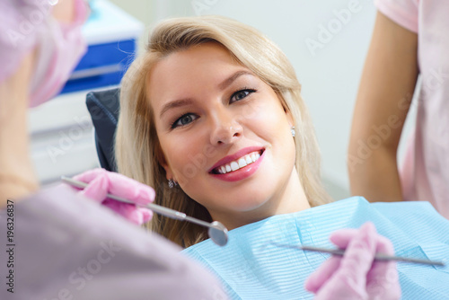 Portrait of young smiling female patient in dental stomatology clinic with white background waiting for doctor