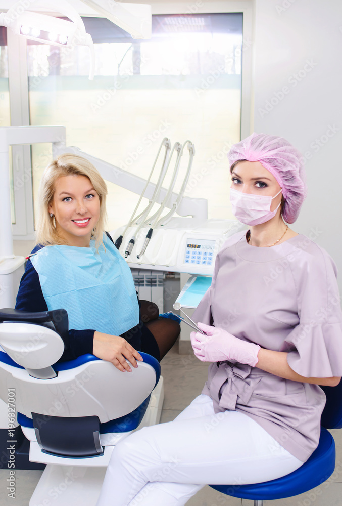 Portrait of young smiling dentists and female patient in dental stomatology clinic with white background Portrait of young smiling dentists and female patient in dental stomatology clinic with white background