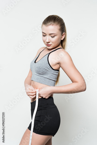 Sportswoman measuring her waist isolated on white © LIGHTFIELD STUDIOS