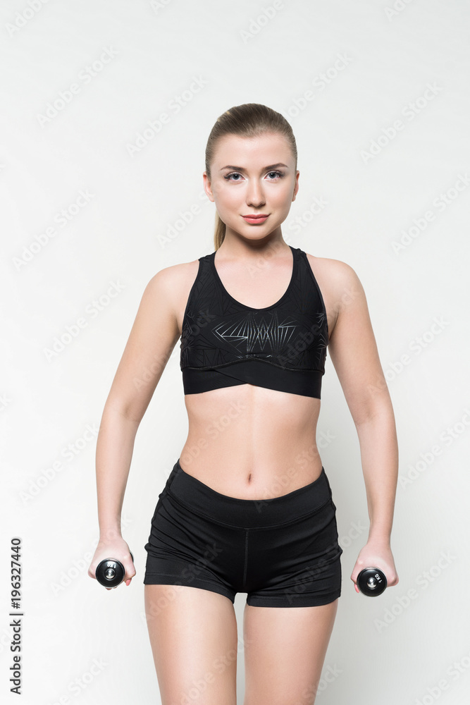 Young woman in sports clothes lifting dumbbells isolated on white Young woman in sports clothes lifting dumbbells isolated on white