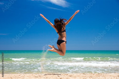 Happy woman in a jump on beach