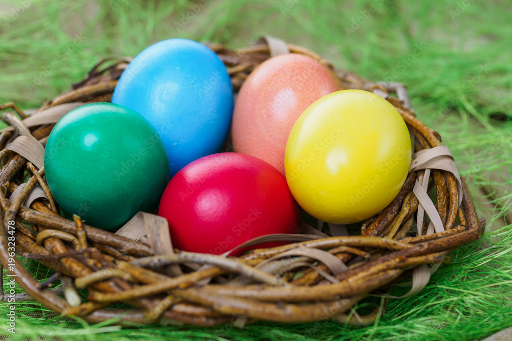 multi-colored easter eggs lie in a nest on a green grassy background close-up multi-colored easter eggs lie in a nest on a green grassy background close-up
