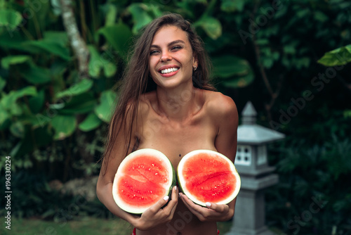 Portrait beautiful brunette girl in swimsuit with watermelon fruit holding in hands. Sexy model with perfect body, cute smile posing. Concept of sport, vegetarian and healthy food