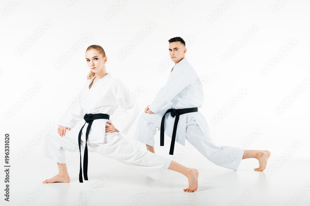 karate fighters stretching legs and looking at camera isolated on white