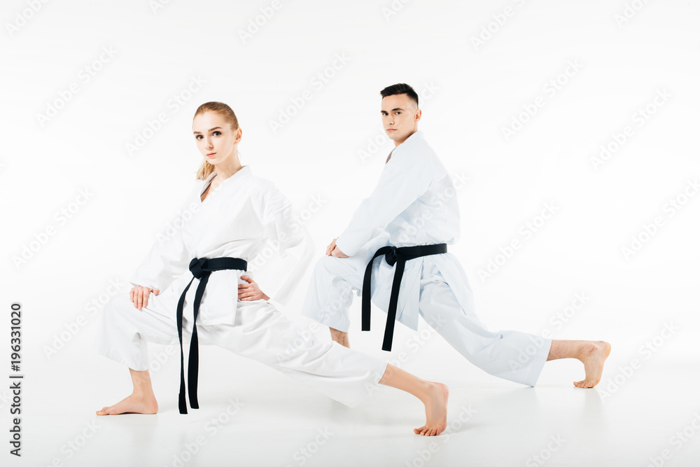 karate fighters stretching legs and looking at camera isolated on white karate fighters stretching legs and looking at camera isolated on white