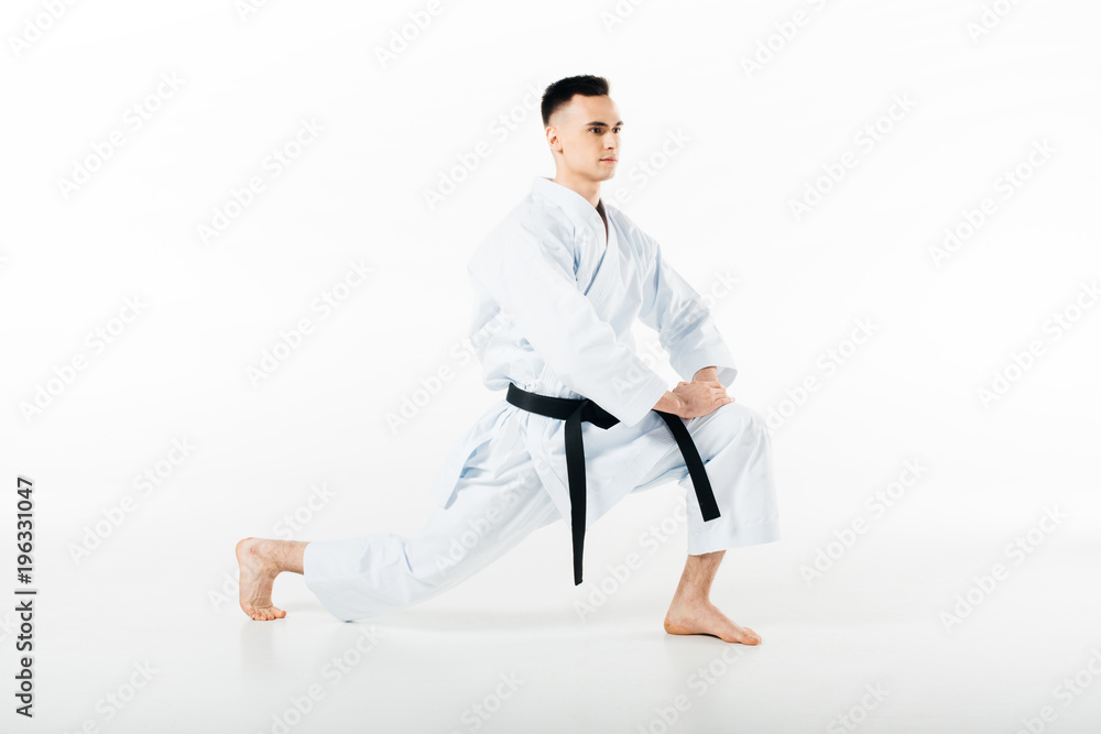 male karate fighter stretching legs isolated on white male karate fighter stretching legs isolated on white