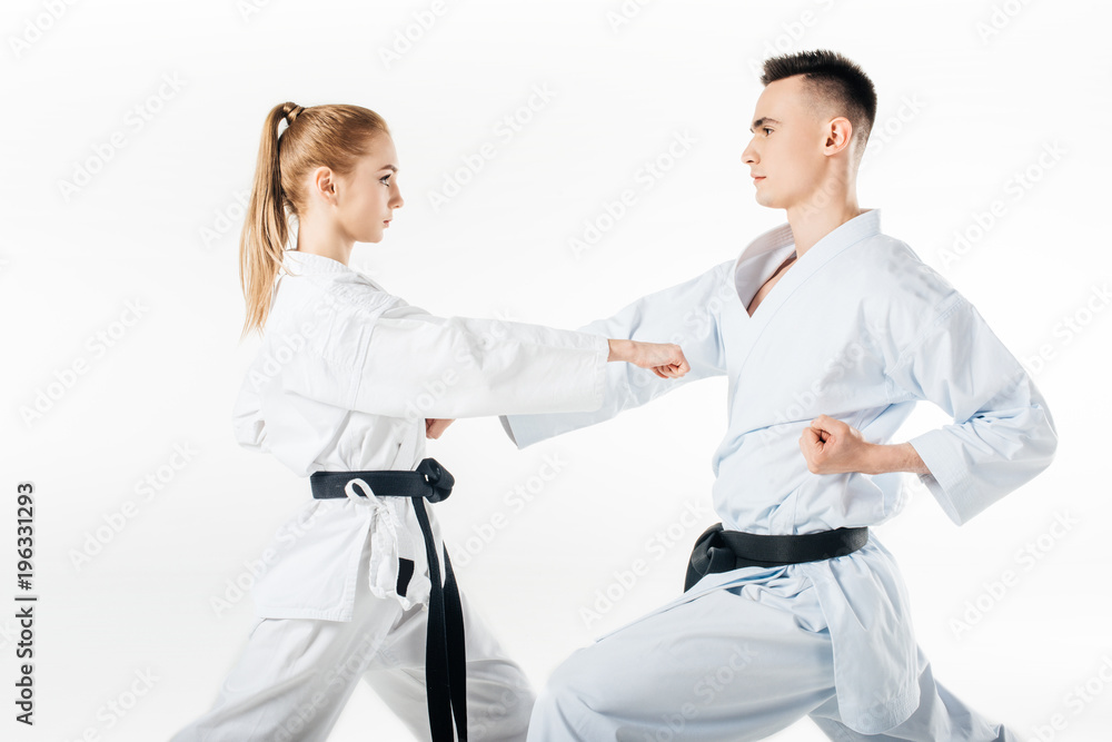 Fototapeta premium side view of karate fighters exercising in kimono isolated on white