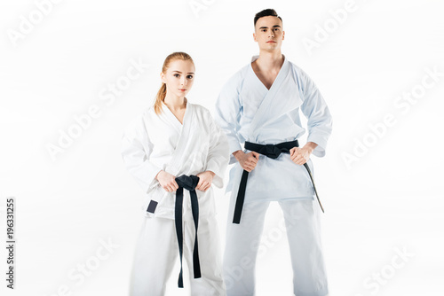 karate fighters holding black belts and looking at camera isolated on white