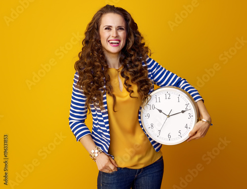 woman isolated on yellow with clock looking at copy space