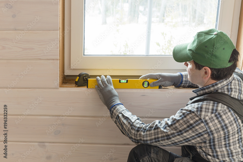 Construction worker thermally insulating eco wooden frame house with wood fiber plates. Finishing the ceiling with a white wooden board. Latvia Construction worker thermally insulating eco wooden frame house with wood fiber plates. Finishing the ceiling with a white wooden board. Latvia