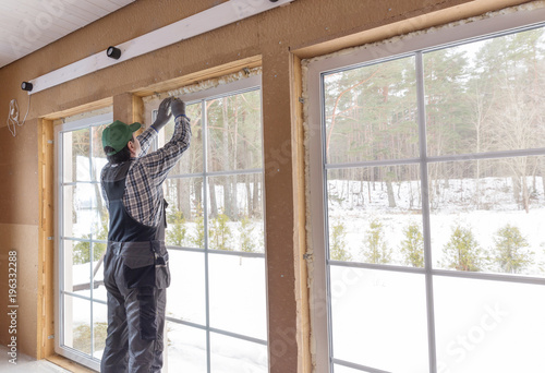 Slika na platnu Construction worker thermally insulating eco wooden frame house with wood fiber plates