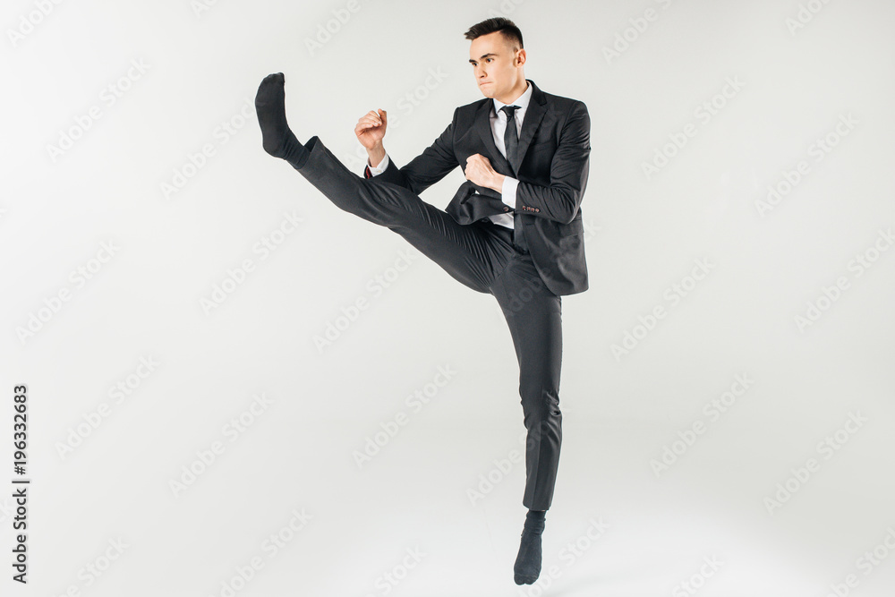 businessman jumping and performing kick in suit isolated on white businessman jumping and performing kick in suit isolated on white