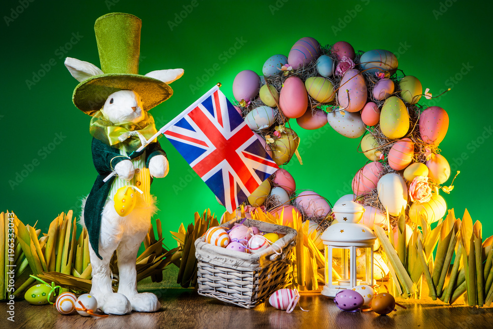 Fototapeta premium The Feast of Easter. Rabbit with colorful eggs. Holiday of Easter in England. The flag of England is held by the Easter bunny.