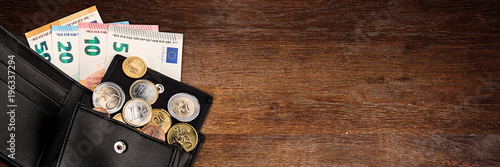 Konstfotografi euro coin and bank note in black  leather wallet on wide wood wooden panorama bu