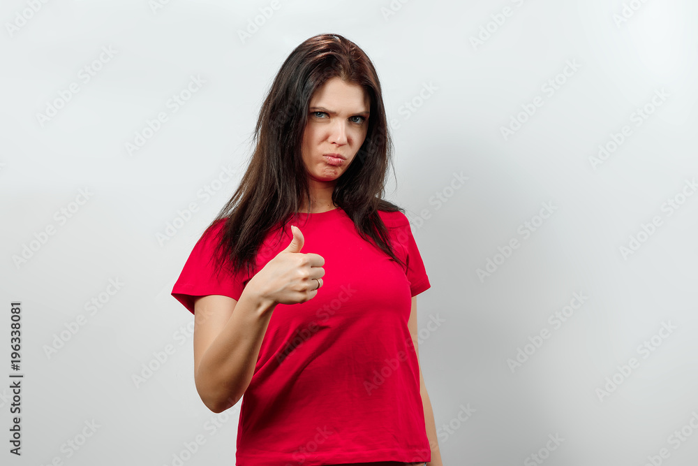 Young, beautiful girl showing a gesture with her hands thumbs up. Isolated on a light background. Different human emotions, feelings of facial expression, attitude, perception, body language, reaction Young, beautiful girl showing a gesture with her hands thumbs up. Isolated on a light background. Different human emotions, feelings of facial expression, attitude, perception, body language, reaction