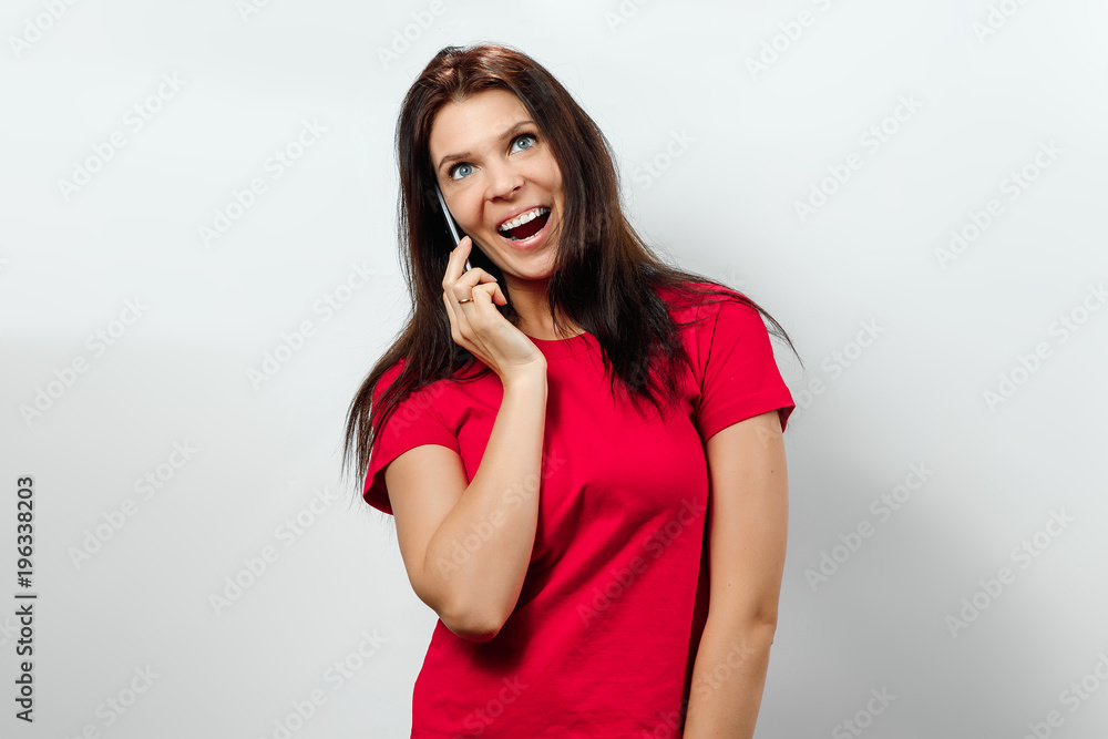 Young, beautiful girl having fun on the phone. Isolated on a light background. Different human emotions, feelings of facial expression, attitude, perception, body language, reaction. Young, beautiful girl having fun on the phone. Isolated on a light background. Different human emotions, feelings of facial expression, attitude, perception, body language, reaction.