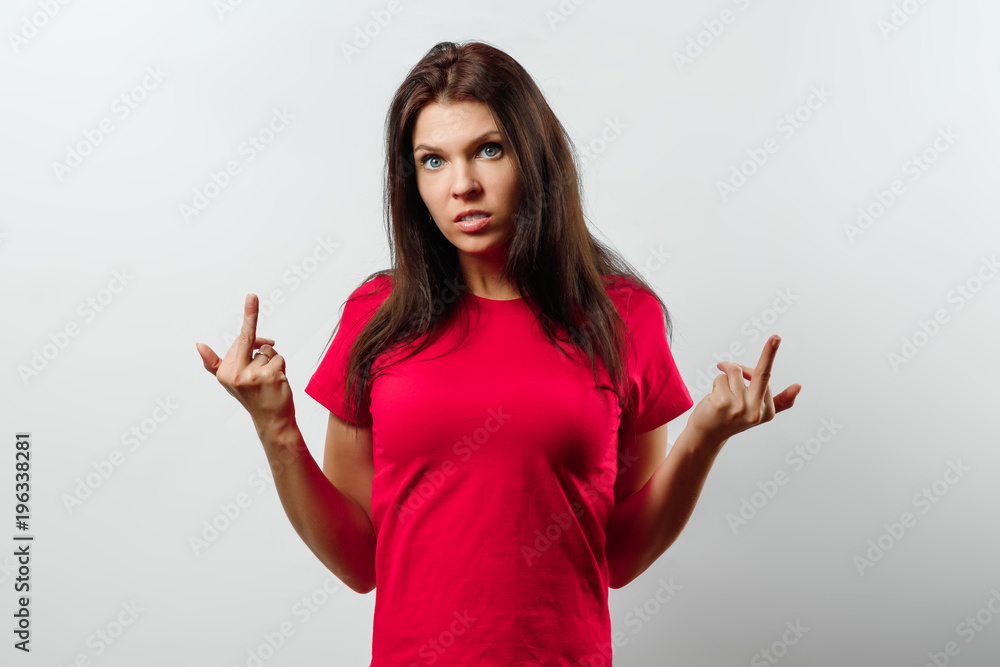 Young, beautiful girl showing the middle finger. Isolated on a light background. Different human emotions, feelings of facial expression, attitude, perception, body language, reaction. Young, beautiful girl showing the middle finger. Isolated on a light background. Different human emotions, feelings of facial expression, attitude, perception, body language, reaction.