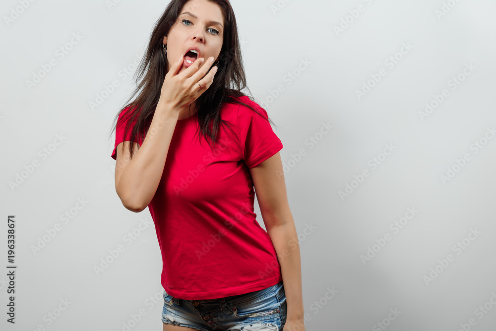 A young, beautiful girl is sexually wiping her lips with her hands. Isolated on a light background. Different human emotions, feelings of facial expression, attitude, perception A young, beautiful girl is sexually wiping her lips with her hands. Isolated on a light background. Different human emotions, feelings of facial expression, attitude, perception