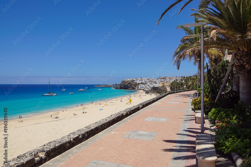 Promenade with tropical plants and flowers along a beach in Morro Jable holiday village, Fuerteventura, Canary Islands, Spain