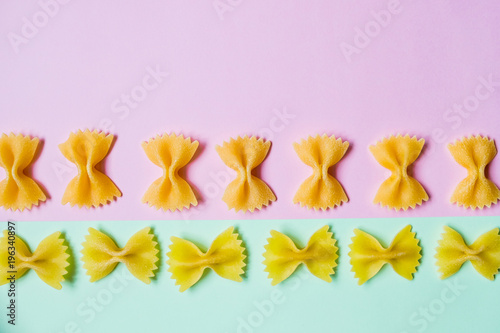 farfalle pasta.Raw pasta on pink and soft green background.food concept -  uncooked pasta