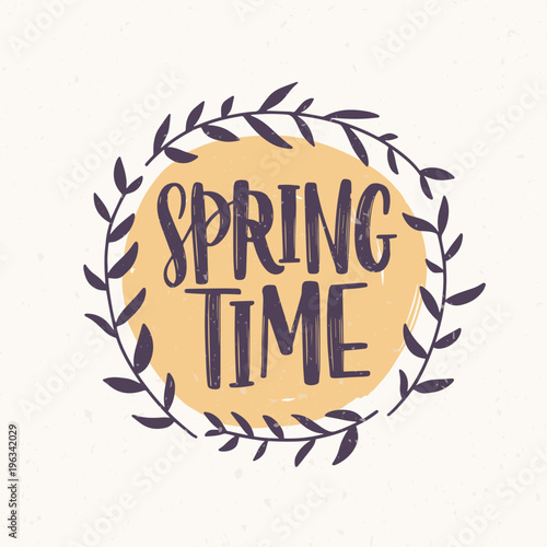 Springtime word written with elegant font inside round frame or wreath made of branches and leaves