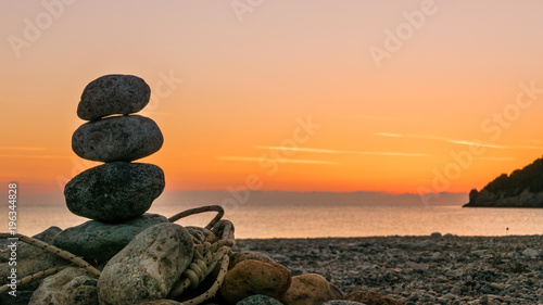 stone stack fireplace with rope on beach at sunrise